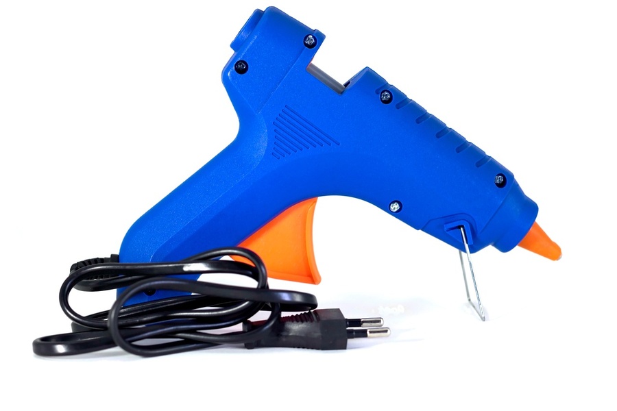 Un pistolet à colle thermique bleu et orange avec son cordon électrique. Utiliser des batteries d'une autre marque sur ses outils : les adaptateurs fiables est une alternative pratique pour vos autres appareils sans fil.