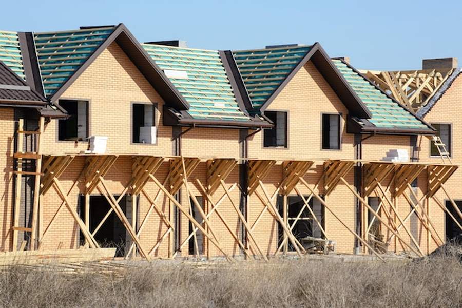 Chantier de maisons en briques avec échafaudages en bois en vue d'une future isolation thermique exterieure.