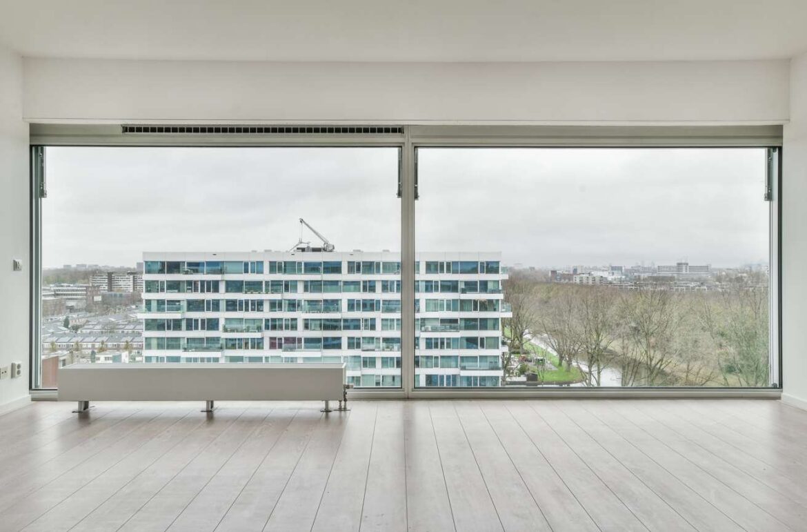 Grand salon lumineux offrant une vue sur la ville à travers une large fenêtre équipée d'un vitrage acoustique haute performance menuiserie pvc.