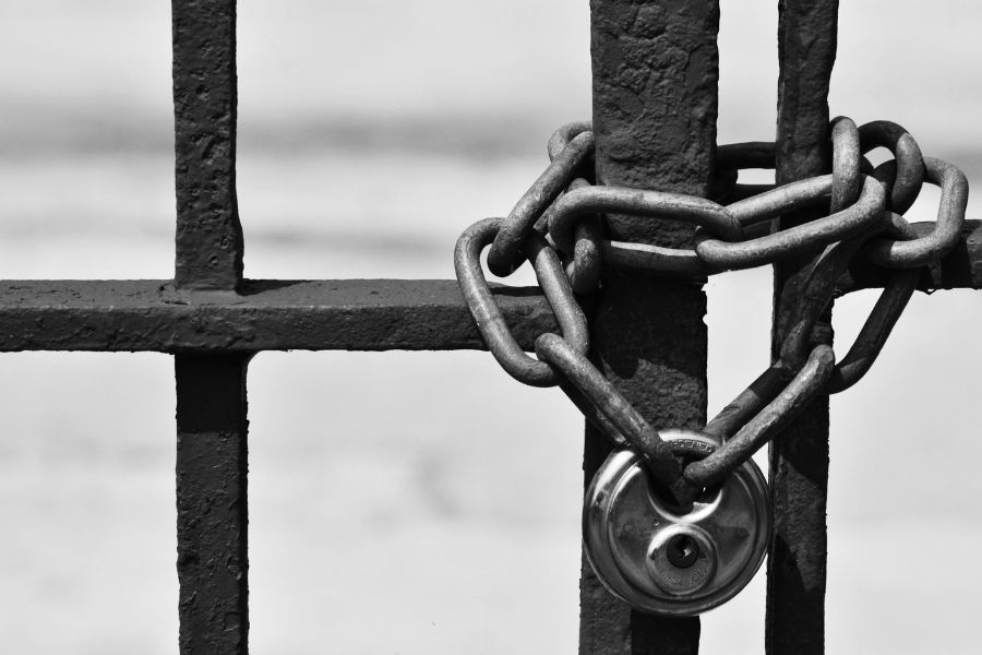 Une chaîne en métal et un cadenas formant une serrure de portail exposée au gel et à la pluie en noir et blanc